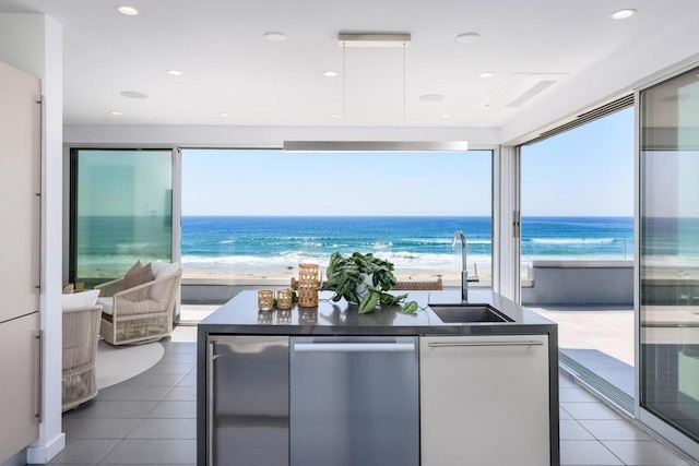 3879 Ocean Front Walk, San Diego, CA 92109 - kitchen with a sink, dishwasher, dark countertops, a center island with sink, and view of water and beach
