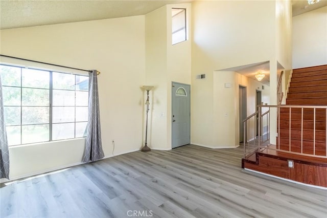 1573 E Brockton Ave, Redlands, CA 92374 - unfurnished living room with high vaulted ceiling, healthy amount of natural light, wood finished floors, stairway, and baseboards