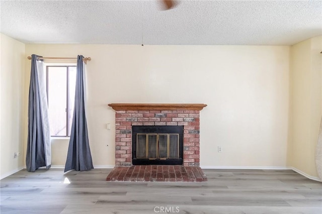 1573 E Brockton Ave, Redlands, CA 92374 - unfurnished living room with wood finished floors, a textured ceiling, a brick fireplace, and baseboards