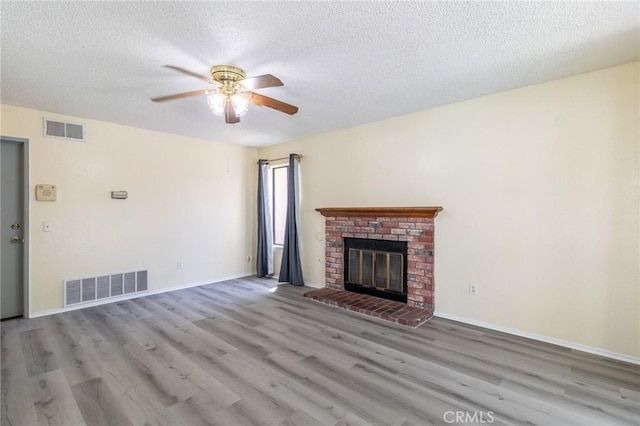 1573 E Brockton Ave, Redlands, CA 92374 - unfurnished living room featuring a ceiling fan, wood finished floors, a textured ceiling, a brick fireplace, and baseboards