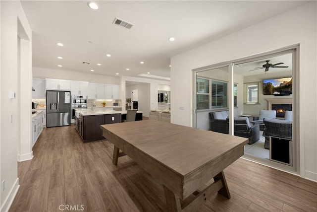 11638 Oakton Way, Corona, CA 92883 - dining room with recessed lighting, wood finished floors, a warm lit fireplace, and a ceiling fan