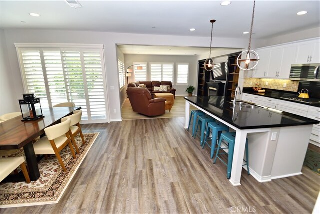 35582 Laurel Tree Ct, Winchester, CA 92596 - kitchen with stainless steel appliances, dark countertops, a breakfast bar, wood finished floors, and white cabinetry