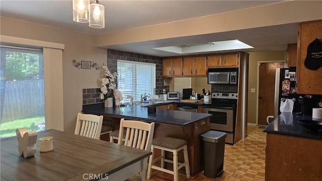 6286 Columbine Rd, Magalia, CA 95954 - kitchen featuring stainless steel appliances, dark countertops, brown cabinetry, and a peninsula