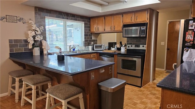6286 Columbine Rd, Magalia, CA 95954 - kitchen with appliances with stainless steel finishes, a peninsula, a sink, brown cabinets, and tasteful backsplash