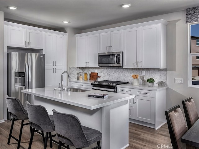 2732 Erebus Ct, Pomona, CA 91767 - kitchen with stainless steel appliances, a sink, a kitchen breakfast bar, decorative backsplash, and white cabinetry