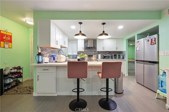 1257 E Grand Ave Unit A, Escondido, CA 92027 - kitchen featuring appliances with stainless steel finishes, wall chimney range hood, a peninsula, light wood-style floors, and backsplash