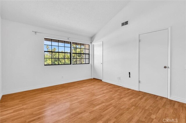 26701 Quail Unit 61, Laguna Hills, CA 92656 - spare room with light wood-style flooring, a textured ceiling, lofted ceiling, and baseboards