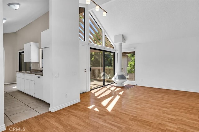 26701 Quail Unit 61, Laguna Hills, CA 92656 - unfurnished living room with a towering ceiling, ornate columns, light wood-style floors, baseboards, and a sink