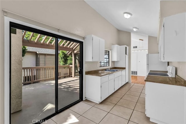 26701 Quail Unit 61, Laguna Hills, CA 92656 - kitchen with a sink, white cabinets, light tile patterned floors, range, and freestanding refrigerator