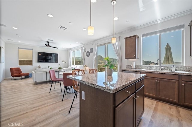 843 Longhorn Way, Rancho Mission Viejo, CA 92694 - kitchen with ornamental molding, light wood finished floors, decorative light fixtures, a kitchen breakfast bar, and recessed lighting