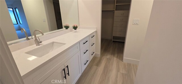 1364 Park Plaza Dr, Long Beach, CA 90804 - bathroom with wood finished floors, vanity, a walk in closet, and baseboards