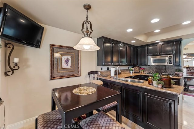 16 Via Barcaza, Coto De Caza, CA 92679 - kitchen with stainless steel microwave, recessed lighting, light stone countertops, dark cabinetry, and a peninsula