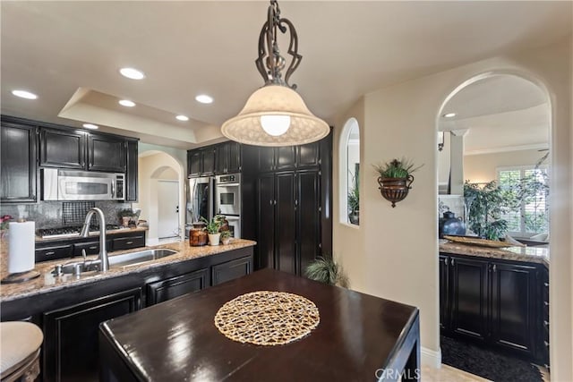 16 Via Barcaza, Coto De Caza, CA 92679 - kitchen with stainless steel appliances, arched walkways, dark cabinetry, backsplash, and pendant lighting