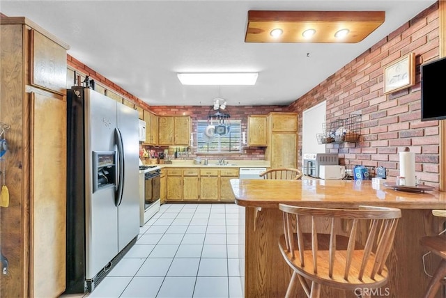 6765 Jadeite Ave, Rancho Cucamonga, CA 91701 - kitchen featuring white appliances, a peninsula, brick wall, light countertops, and a sink