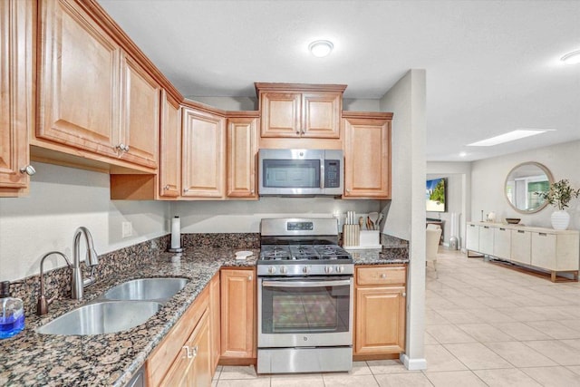 970 Carlsbad St, San Diego, CA 92114 - kitchen with stainless steel appliances, a sink, a skylight, dark stone counters, and light tile patterned floors