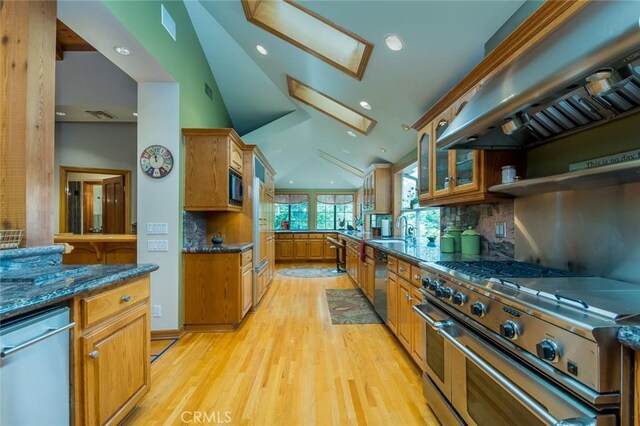 2410 W Cinco Casitas Ln, La Crescenta, CA 91214 - kitchen featuring appliances with stainless steel finishes, a skylight, wall chimney exhaust hood, light wood-style flooring, and brown cabinetry
