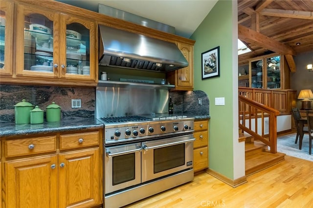 2410 W Cinco Casitas Ln, La Crescenta, CA 91214 - kitchen featuring double oven range, wall chimney exhaust hood, light wood finished floors, tasteful backsplash, and glass insert cabinets
