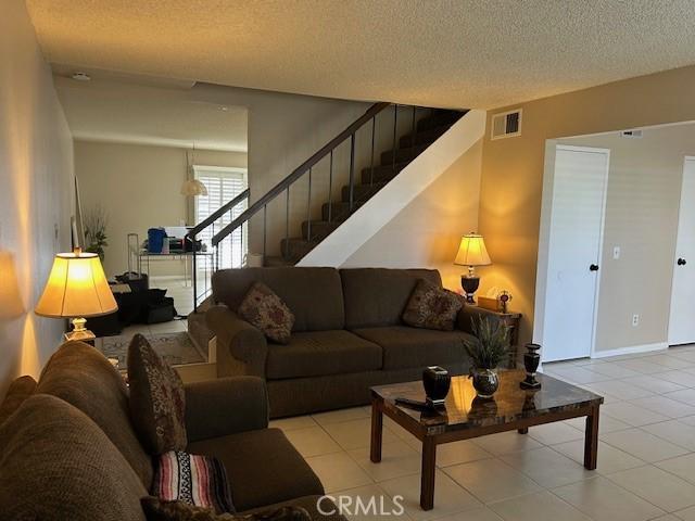 61765 Arroyo Rd Unit 5, Palm Springs, CA 92264 - living room featuring stairs, a textured ceiling, and tile patterned floors