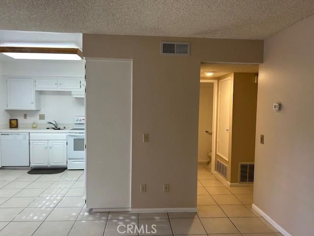 61765 Arroyo Rd Unit 5, Palm Springs, CA 92264 - kitchen with white appliances, light countertops, light tile patterned floors, a textured ceiling, and white cabinetry