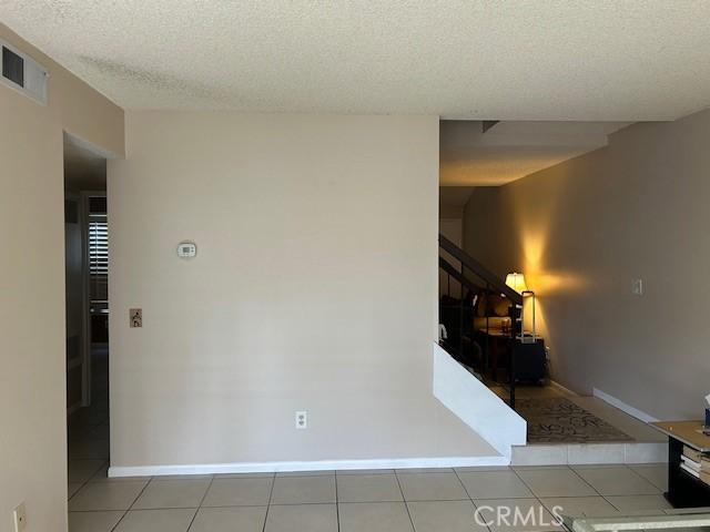 61765 Arroyo Rd Unit 5, Palm Springs, CA 92264 - empty room featuring a textured ceiling, stairway, and tile patterned floors
