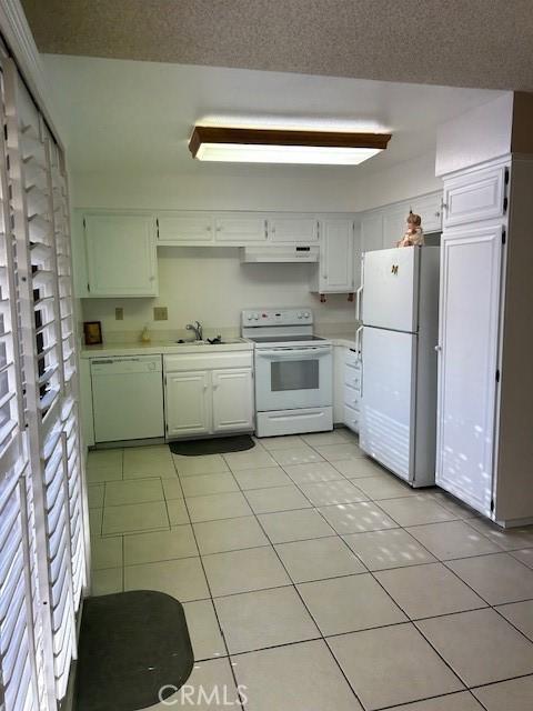61765 Arroyo Rd Unit 5, Palm Springs, CA 92264 - kitchen featuring white appliances, exhaust hood, light countertops, light tile patterned flooring, and white cabinets