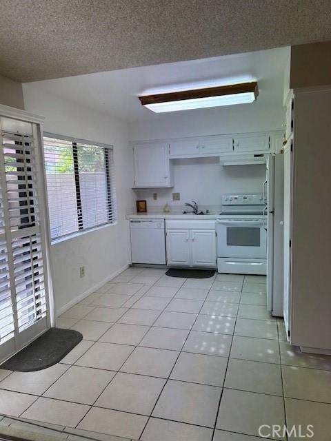 61765 Arroyo Rd Unit 5, Palm Springs, CA 92264 - kitchen with white appliances, light countertops, light tile patterned flooring, extractor fan, and white cabinets