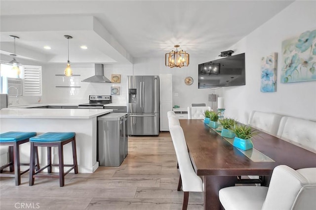 810 Edgewood St Unit 302, Inglewood, CA 90302 - kitchen with appliances with stainless steel finishes, wall chimney range hood, a chandelier, light wood finished floors, and recessed lighting