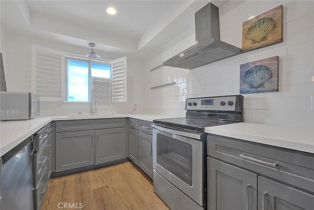 810 Edgewood St Unit 302, Inglewood, CA 90302 - kitchen with appliances with stainless steel finishes, gray cabinets, wall chimney exhaust hood, a sink, and light wood-type flooring