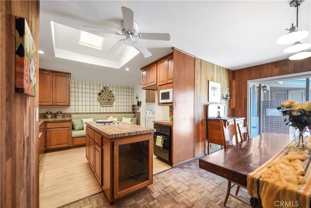 14242 Clarissa Ln, North Tustin, CA 92705 - kitchen with white microwave, washer and dryer, a ceiling fan, a kitchen island, and a raised ceiling