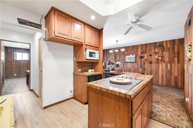 14242 Clarissa Ln, North Tustin, CA 92705 - kitchen with white appliances, wooden walls, a kitchen island, a ceiling fan, and light wood-style flooring