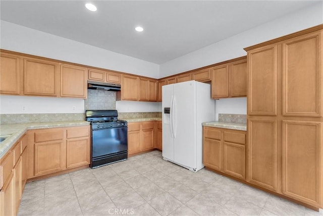 1760 Terrace Ave, Colton, CA 92324 - kitchen with black gas stove, white fridge with ice dispenser, under cabinet range hood, light countertops, and recessed lighting