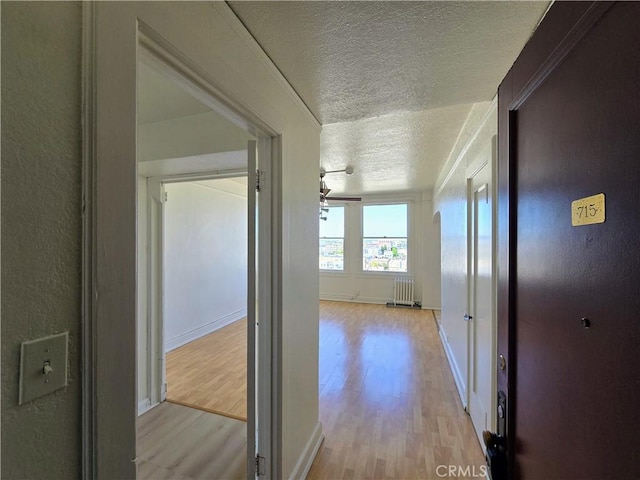 455 E Ocean Blvd Unit 715, Long Beach, CA 90802 - corridor featuring a textured ceiling, wood finished floors, baseboards, and radiator heating unit