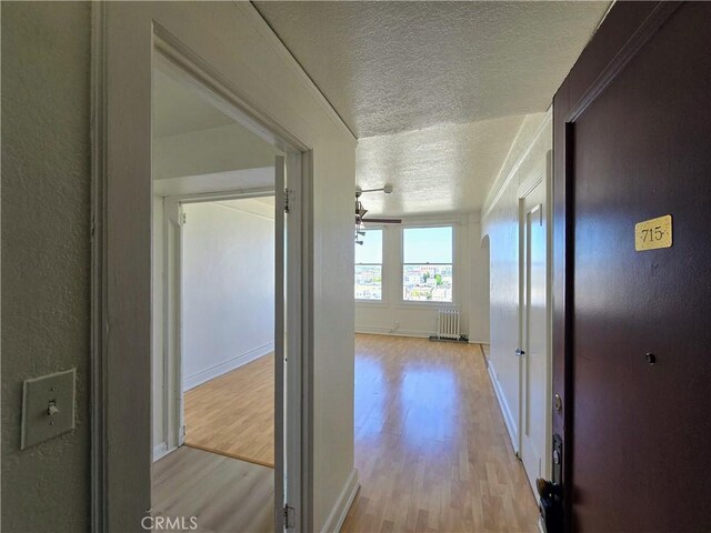 455 E Ocean Blvd Unit 715, Long Beach, CA 90802 - hallway featuring a textured ceiling, light wood finished floors, and radiator