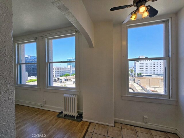 455 E Ocean Blvd Unit 715, Long Beach, CA 90802 - unfurnished room featuring radiator heating unit, a ceiling fan, light wood-type flooring, arched walkways, and a city view