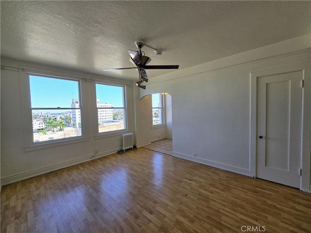 455 E Ocean Blvd Unit 715, Long Beach, CA 90802 - empty room featuring radiator, wood finished floors, a textured ceiling, ceiling fan, and arched walkways
