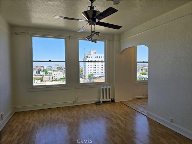 455 E Ocean Blvd Unit 715, Long Beach, CA 90802 - spare room with radiator, healthy amount of natural light, wood finished floors, a ceiling fan, and a textured ceiling