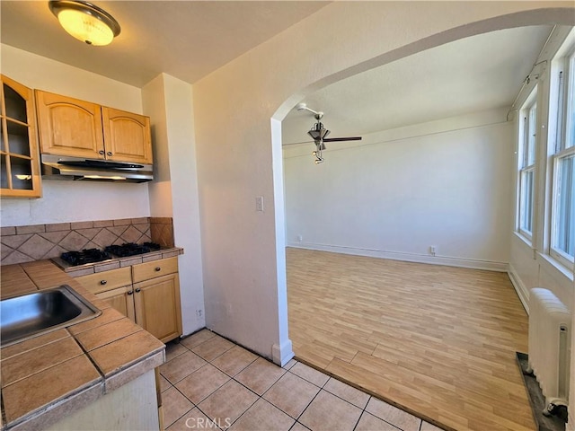 455 E Ocean Blvd Unit 715, Long Beach, CA 90802 - kitchen with under cabinet range hood, arched walkways, radiator heating unit, gas cooktop, and tile countertops
