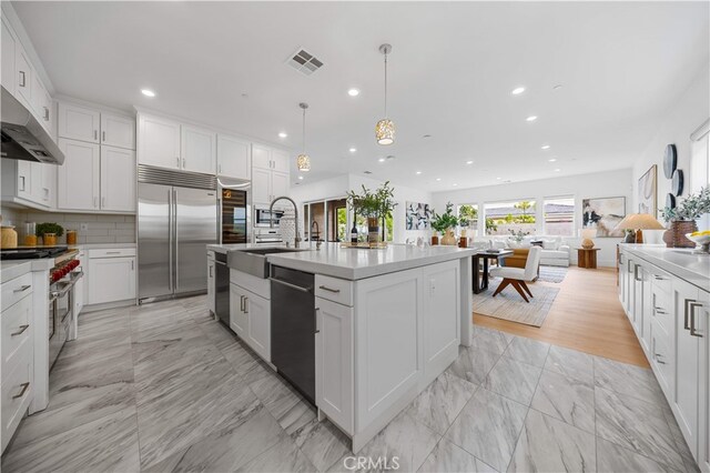 72 Crater, Irvine, CA 92618 - kitchen with high end appliances, light marble finish floors, a sink, white cabinets, and recessed lighting