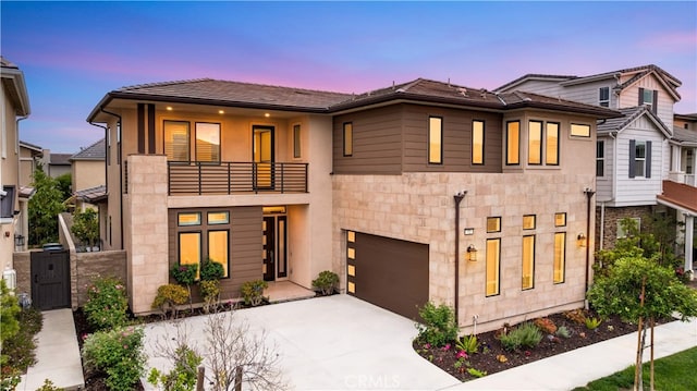 72 Crater, Irvine, CA 92618 - view of front of home with a balcony, concrete driveway, stone siding, and a garage