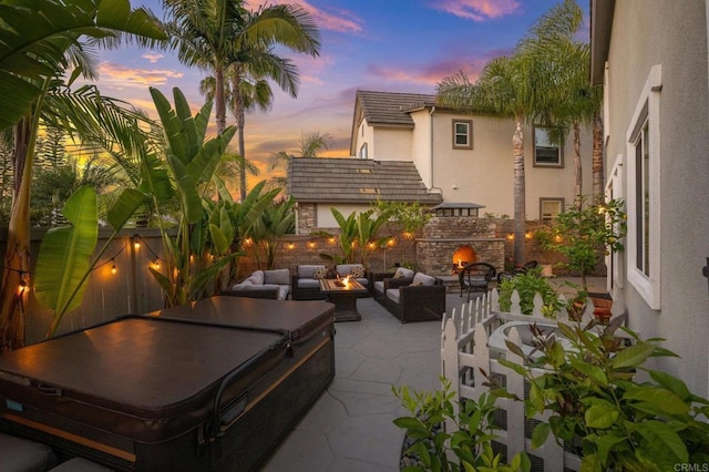 2185 Twain Ave, Carlsbad, CA 92008 - patio terrace at dusk with a patio, an outdoor living space with a fireplace, a hot tub, and a fenced backyard