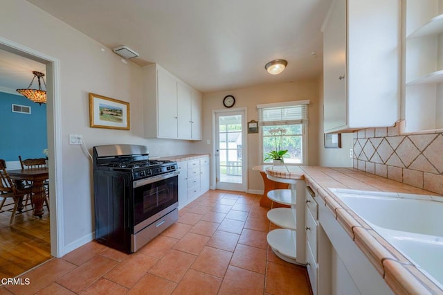 1736 Craig Ave, Altadena, CA 91001 - kitchen with stainless steel gas stove, tile countertops, open shelves, white cabinetry, and decorative backsplash
