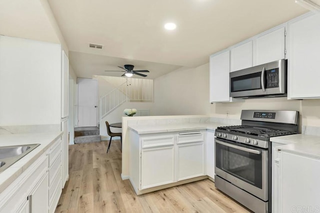 10264 Michala Pl, Santee, CA 92071 - kitchen with stainless steel appliances, a peninsula, white cabinetry, light wood-style flooring, and recessed lighting