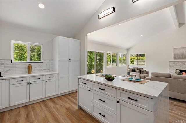 1208 Via Viento Suave, San Marcos, CA 92078 - kitchen featuring decorative backsplash, open floor plan, light wood-style floors, white cabinetry, and high vaulted ceiling