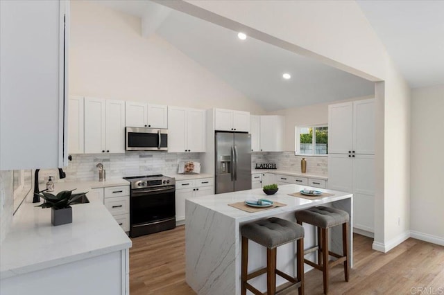 1208 Via Viento Suave, San Marcos, CA 92078 - kitchen with stainless steel appliances, a kitchen bar, a sink, light wood finished floors, and beam ceiling