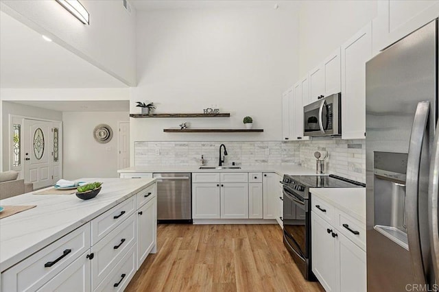1208 Via Viento Suave, San Marcos, CA 92078 - kitchen featuring appliances with stainless steel finishes, a sink, white cabinetry, tasteful backsplash, and a towering ceiling