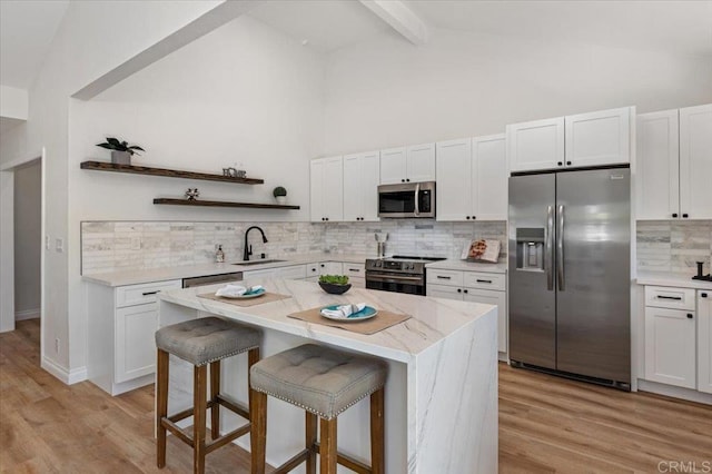 1208 Via Viento Suave, San Marcos, CA 92078 - kitchen with stainless steel appliances, a sink, open shelves, a breakfast bar area, and decorative backsplash