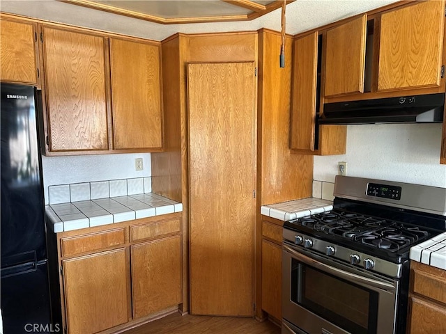 37824 Queensboro Ct, Palmdale, CA 93552 - kitchen featuring stainless steel gas range, freestanding refrigerator, ventilation hood, and tile counters