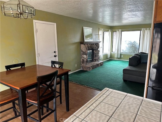 37824 Queensboro Ct, Palmdale, CA 93552 - dining area with a chandelier, a textured ceiling, a stone fireplace, baseboards, and carpet