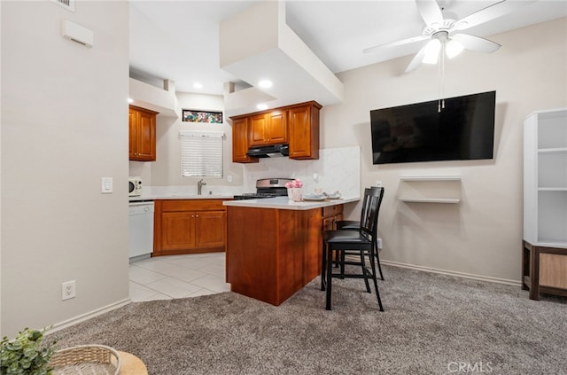 17191 Corbina Ln Unit 109, Huntington Beach, CA 92649 - kitchen with white appliances, under cabinet range hood, a breakfast bar area, brown cabinets, and ceiling fan