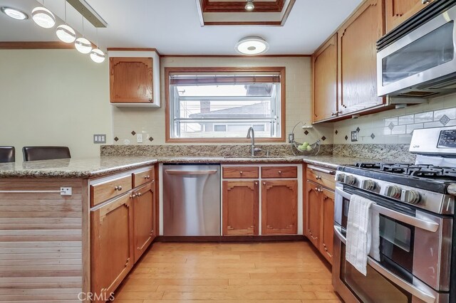 2818 W 166th St, Torrance, CA 90504 - kitchen featuring stainless steel appliances, light wood-style flooring, a peninsula, backsplash, and crown molding